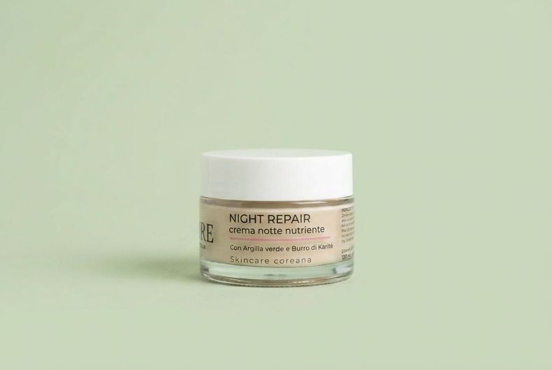 Vasetto di crema riparatrice notte con coperchio bianco su sfondo verde chiaro.