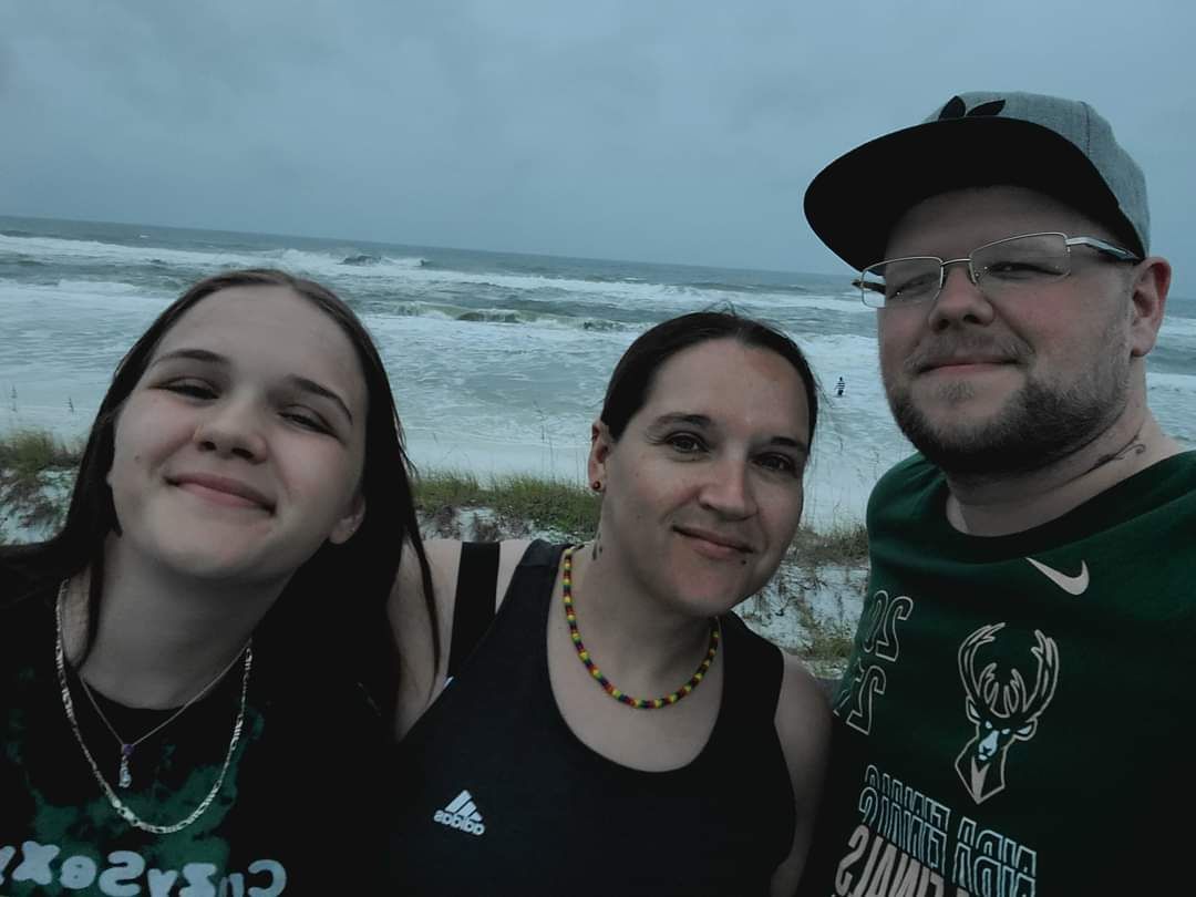 A man and two women pose for a picture on the beach