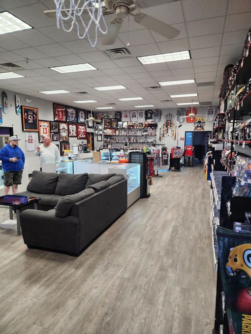 Sports memorabilia store interior with gray couch, display cases, and merchandise on walls and shelves