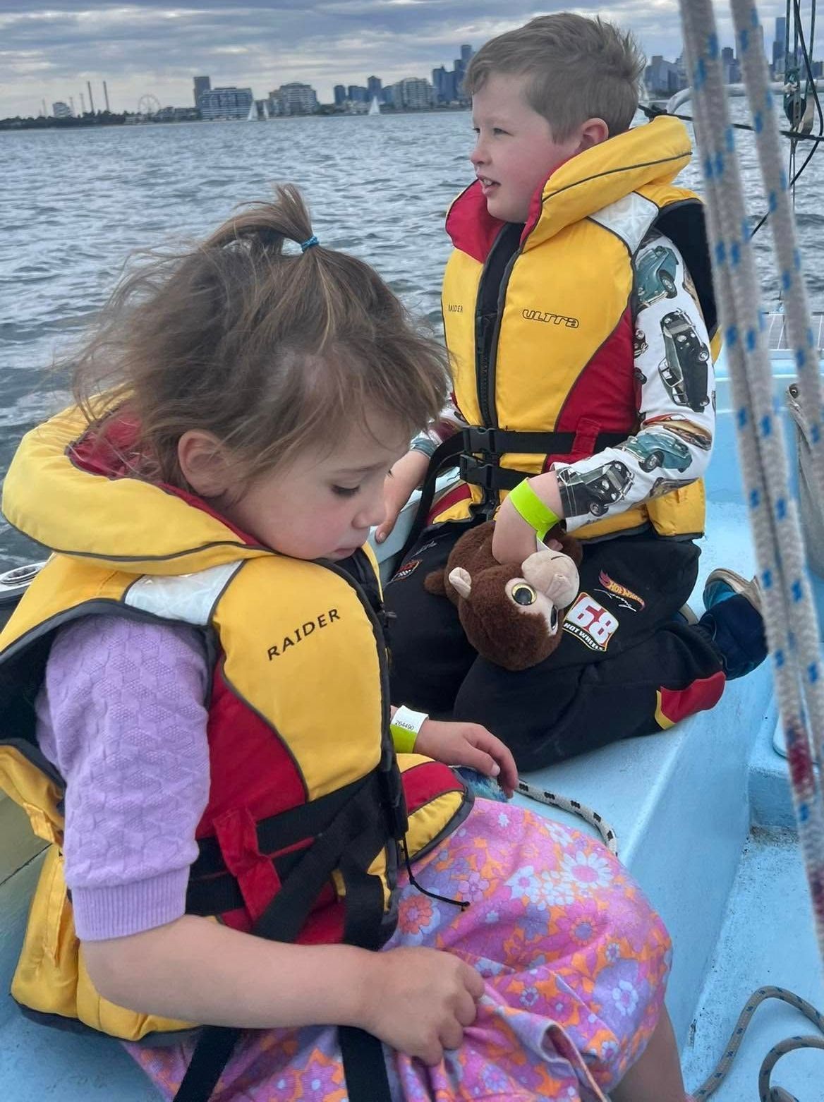 A boy and a girl are sitting on a boat wearing life jackets