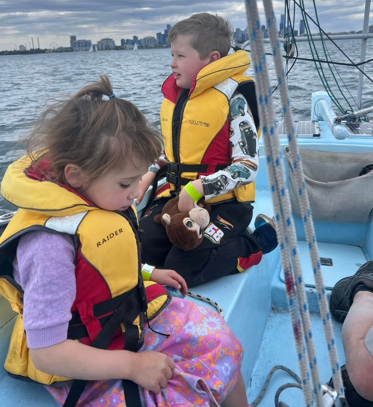 A boy and a girl are sitting on a boat wearing life jackets