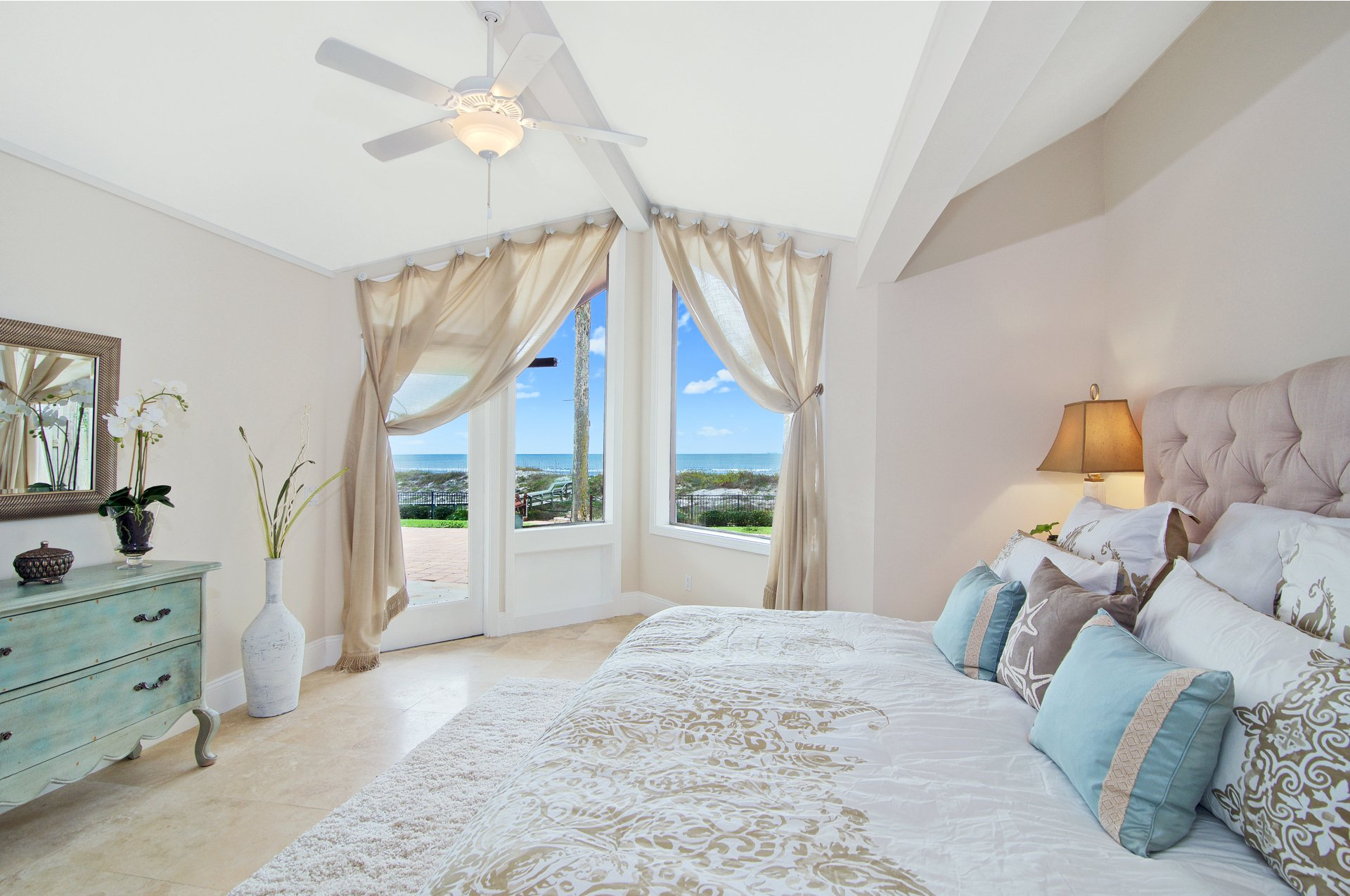 A bedroom with a bed , dresser , mirror and ceiling fan.