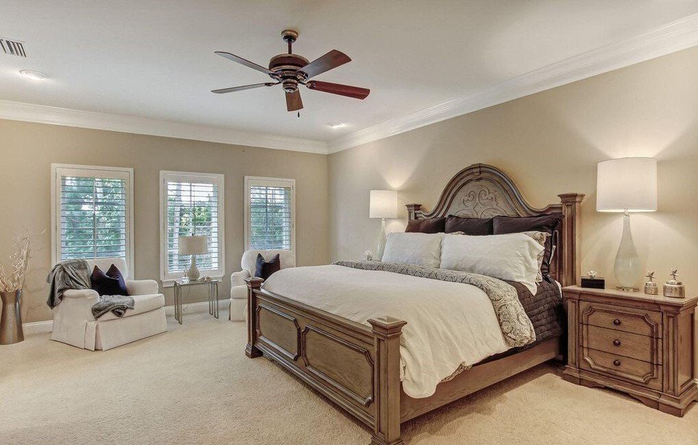 A bedroom with a large bed and a ceiling fan.