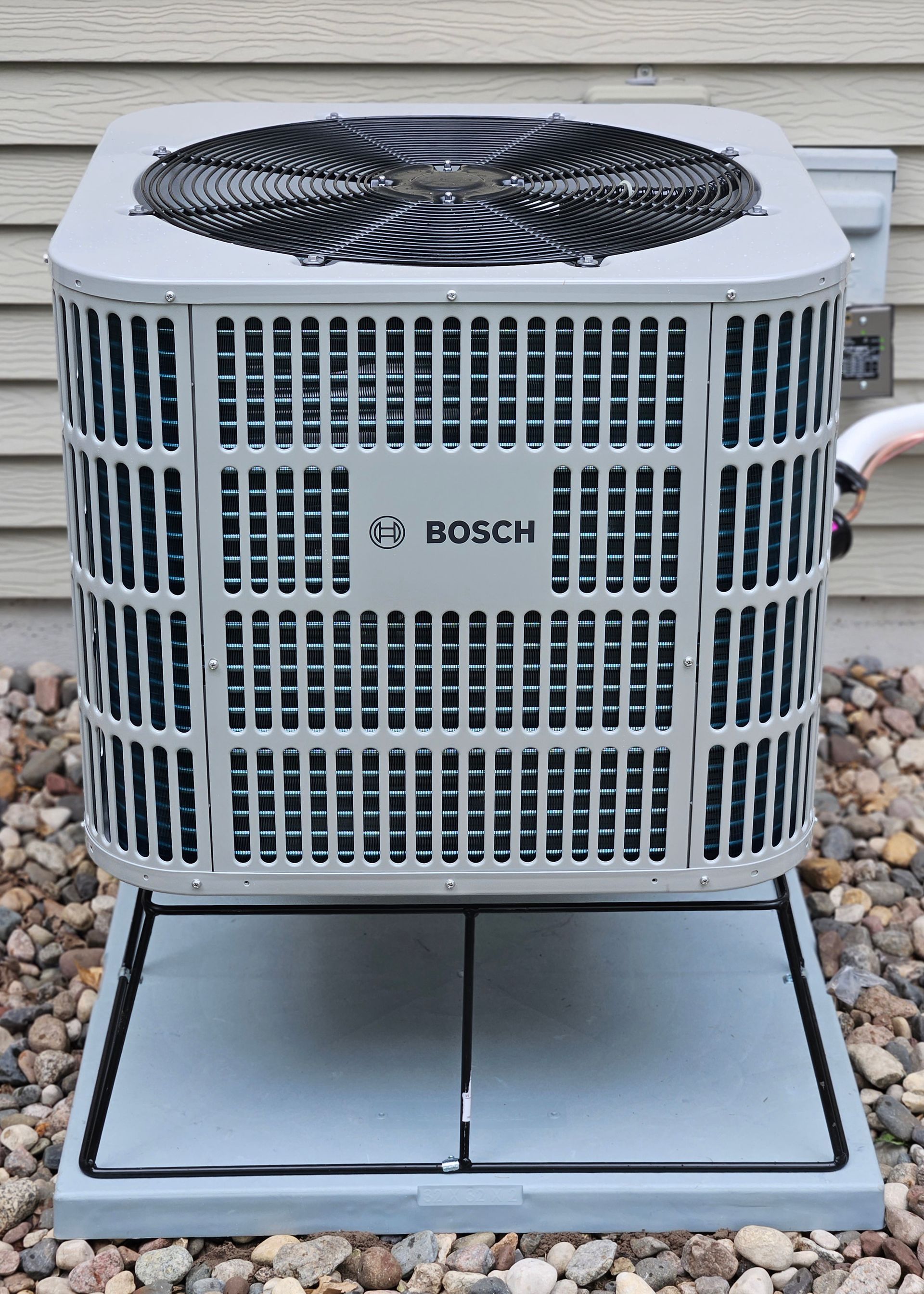 A bosch air conditioner is sitting on top of a pile of rocks.