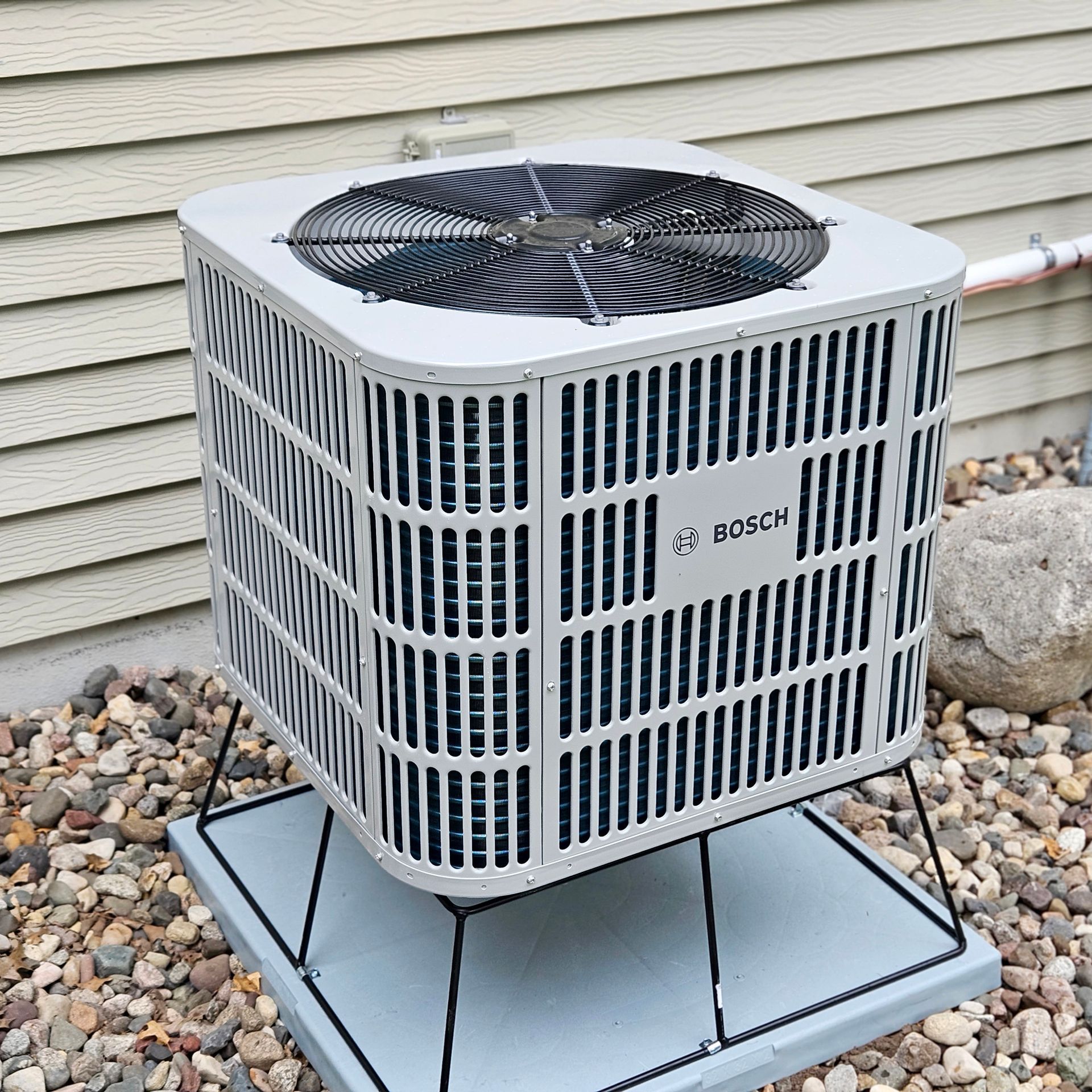 A bosch air conditioner sits outside of a house