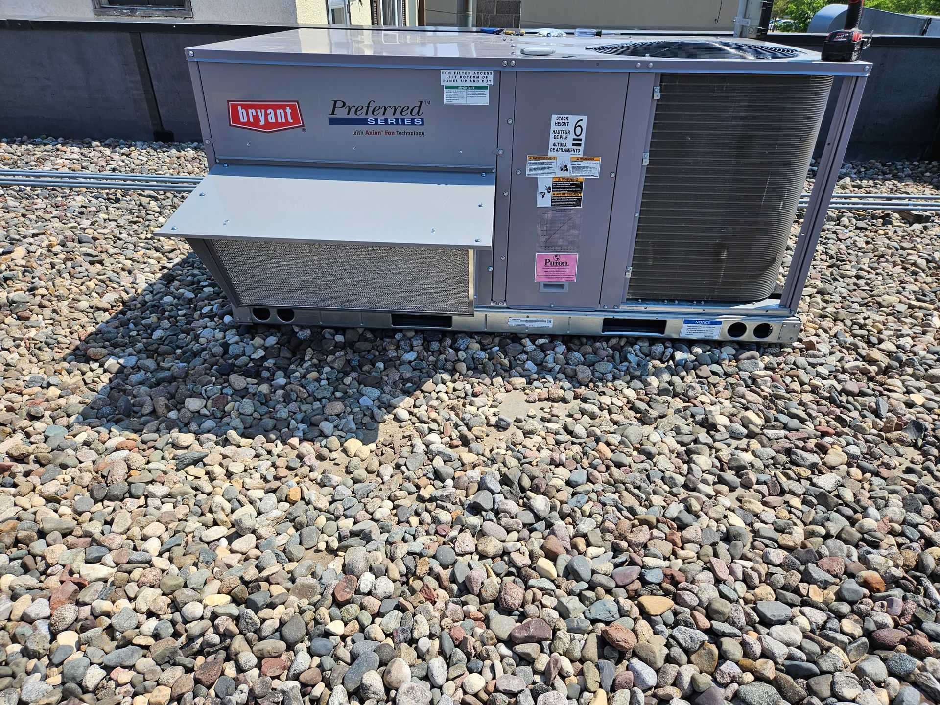 A large air conditioner is sitting on top of a pile of rocks.
