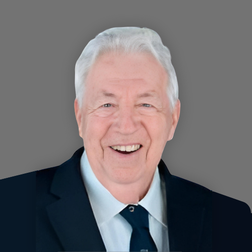 A man wearing glasses and a suit is smiling