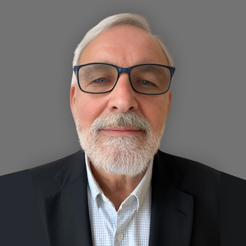 A man wearing glasses and a suit is smiling