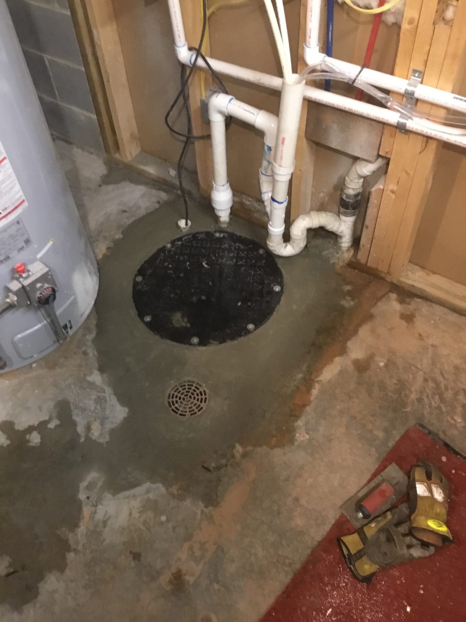 A basement with a water heater and a sump pump.