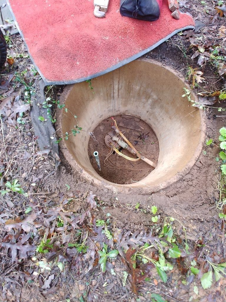 A person is standing on a red rug next to a hole in the ground.