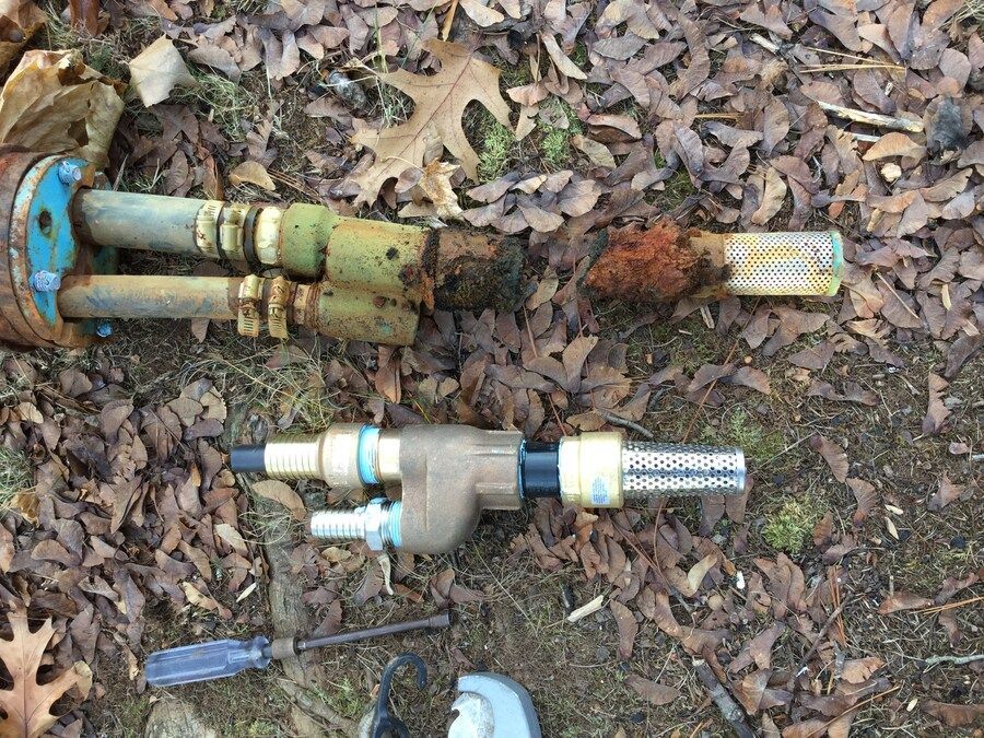 A couple of pipes are laying on the ground next to a screwdriver and a grinder.