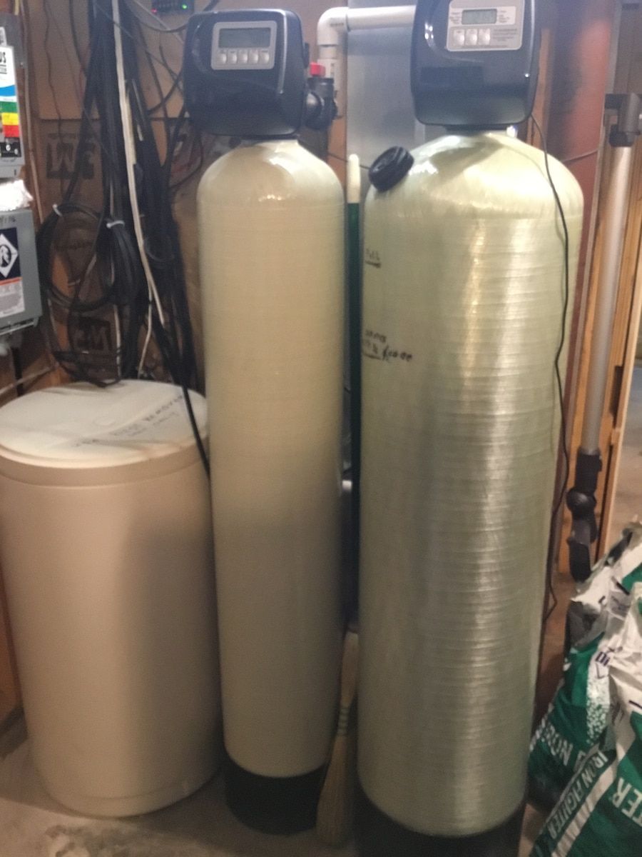 Two water filters are sitting next to each other in a basement.