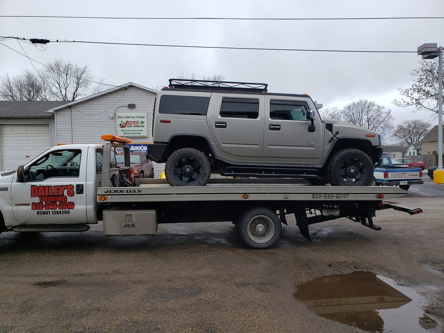 White car on red tow truck, on a street.