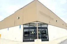 Front entrance of a beige and white building with glass doors under a sloped roof