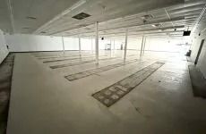 Empty industrial warehouse with long floor tracks under a bright ceiling