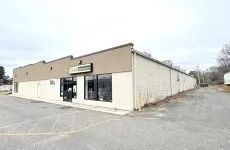 Small beige storefront in an empty parking lot on an overcast day