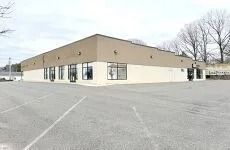 Empty parking lot outside a tan commercial building with large windows on a cloudy day