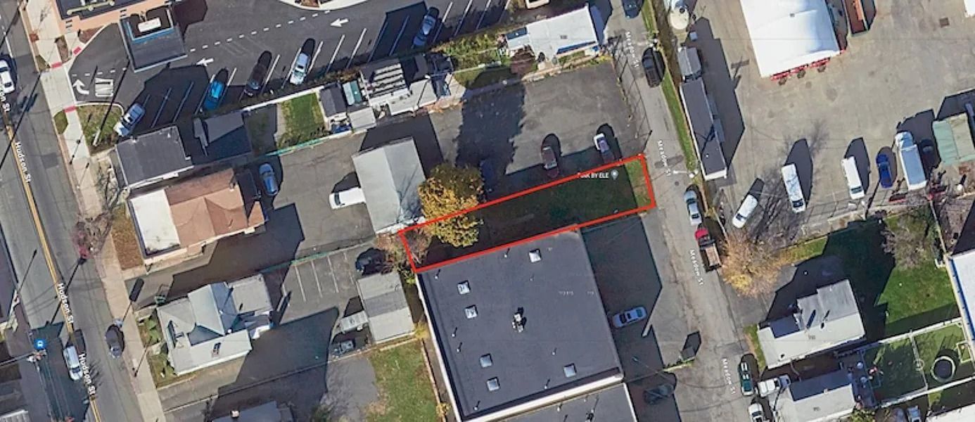 Aerial view of houses and streets, with a red-outlined roof area in the center.