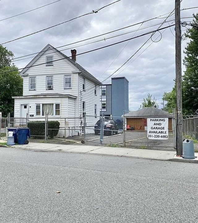 White house beside a fenced parking area with a 