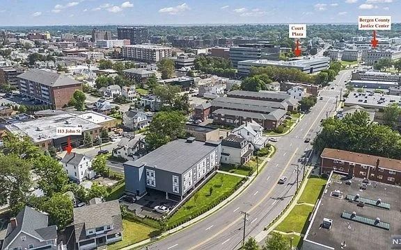 Aerial view of a suburban neighborhood with curving roads, houses, trees, and commercial buildings.