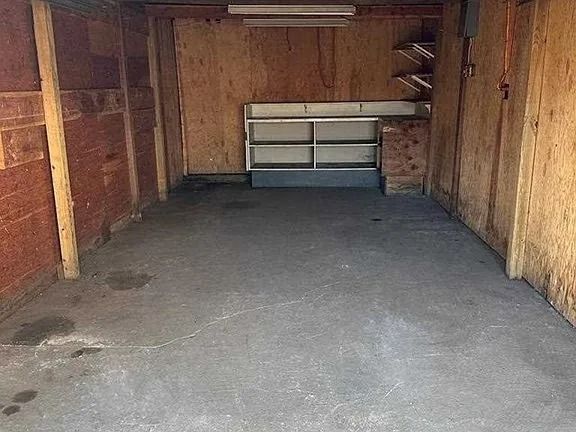 Empty wooden garage with a concrete floor and shelves at the back