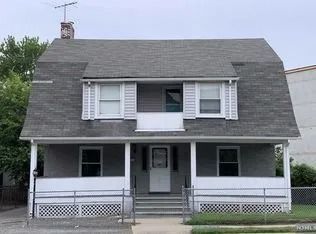 Gray two-story house with front porch, white trim, and central steps behind a low fence.