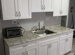 Kitchen counter with sink, white cabinets, and a granite backsplash, with a toaster oven on the left.
