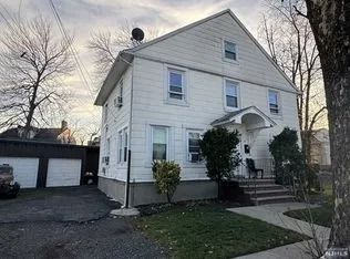 Two-story white house with detached garage, front steps, and a small front yard at dusk