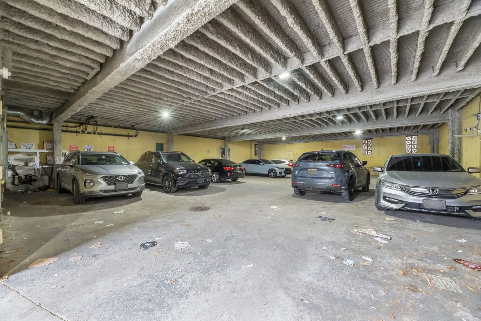 Indoor parking garage with several parked cars and a low concrete ceiling