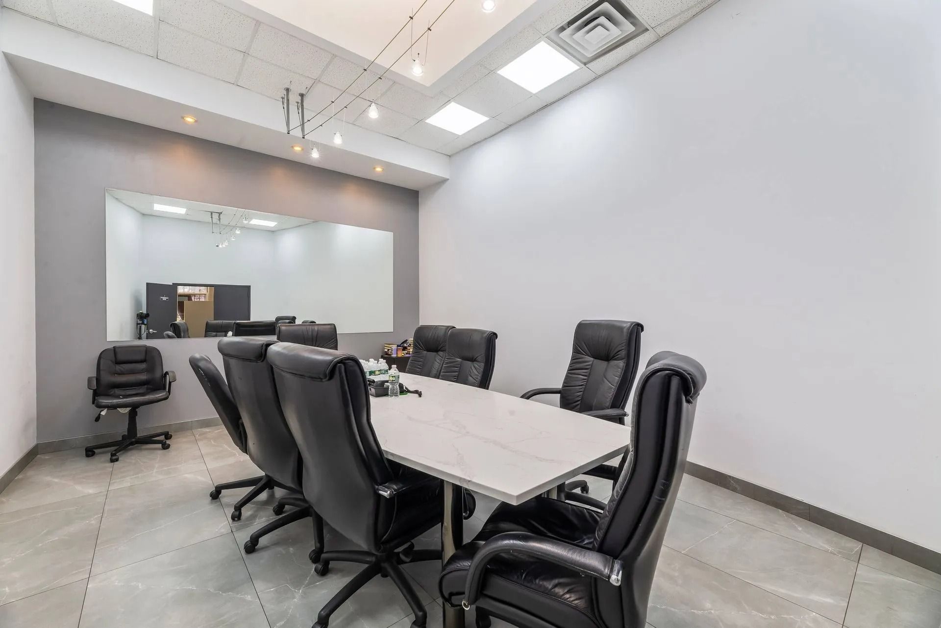 Modern conference room with black chairs, white table, and glass wall partition