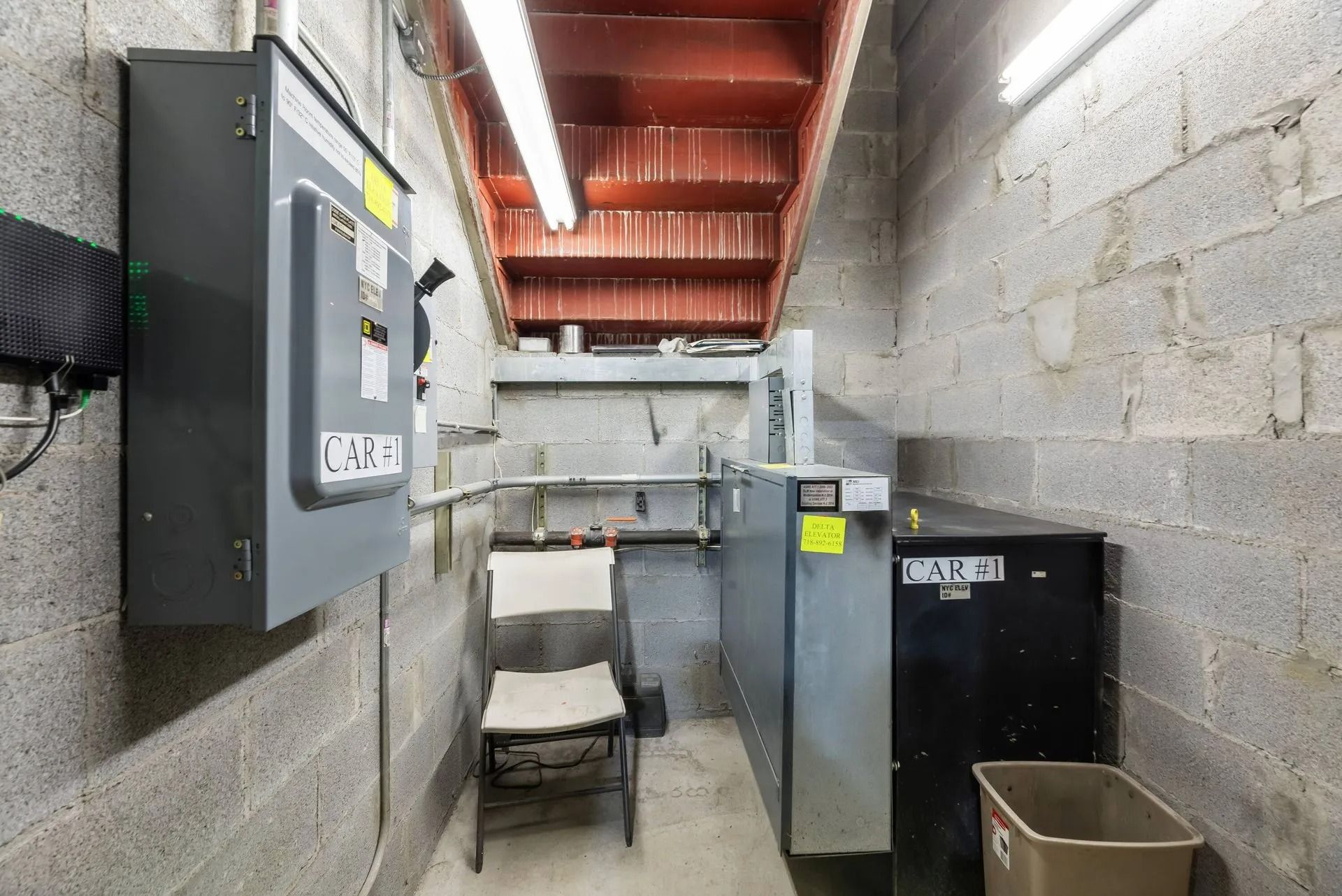 Basement utility room with electrical panels, metal cabinets, and cinder block walls