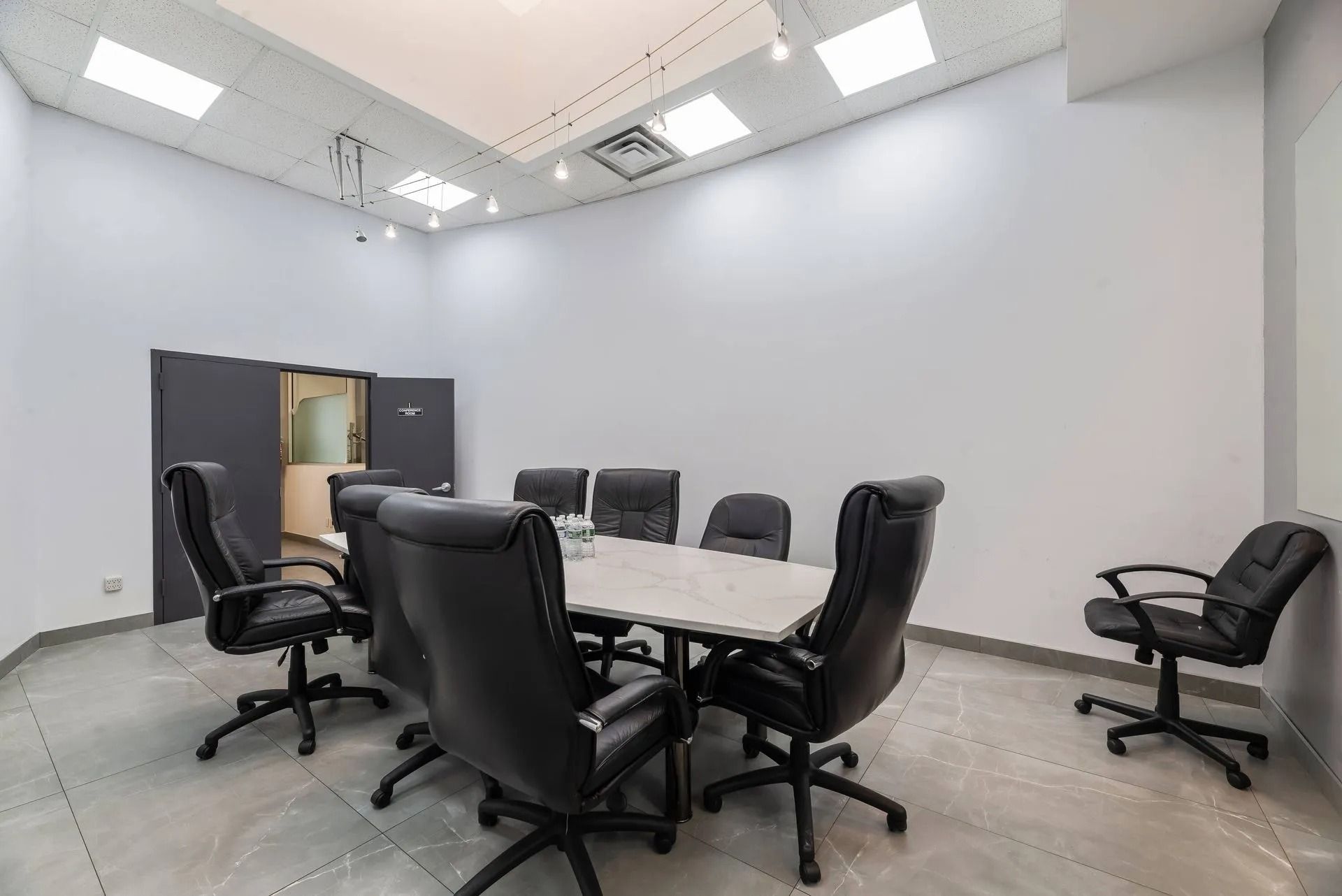 Modern conference room with round table and black office chairs under bright ceiling lights