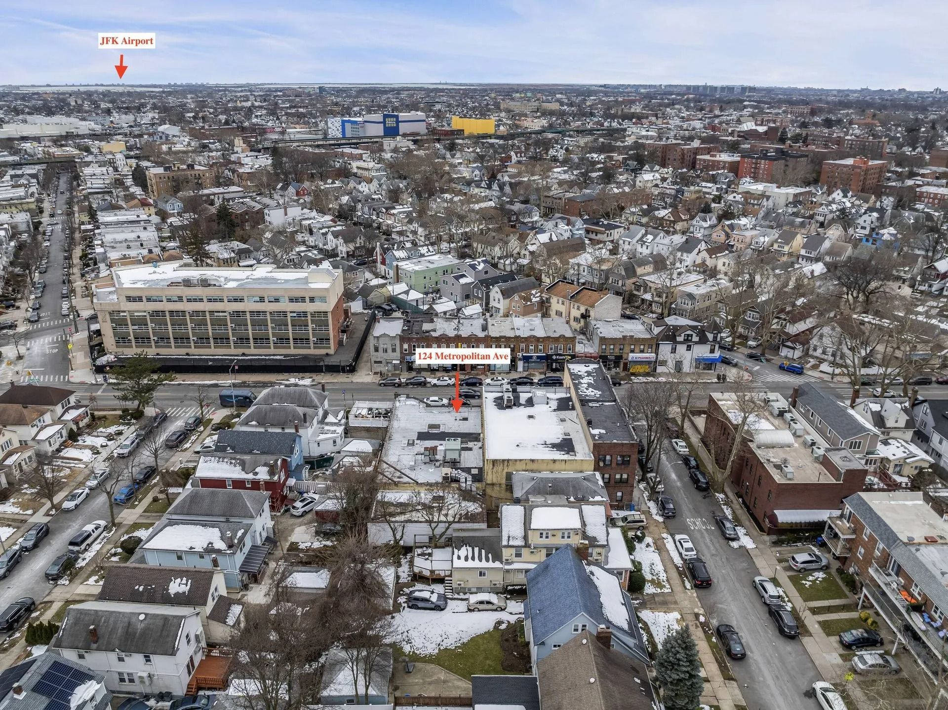 Aerial view of a snowy town with houses, streets, and a large building in the foreground