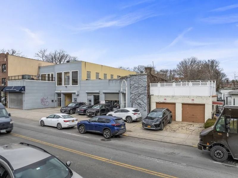Street view of a small auto repair lot with parked cars and a garage under a blue sky