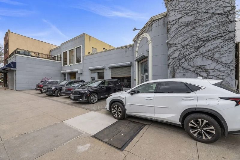 Parked cars beside a modern building with a large tree mural on the wall