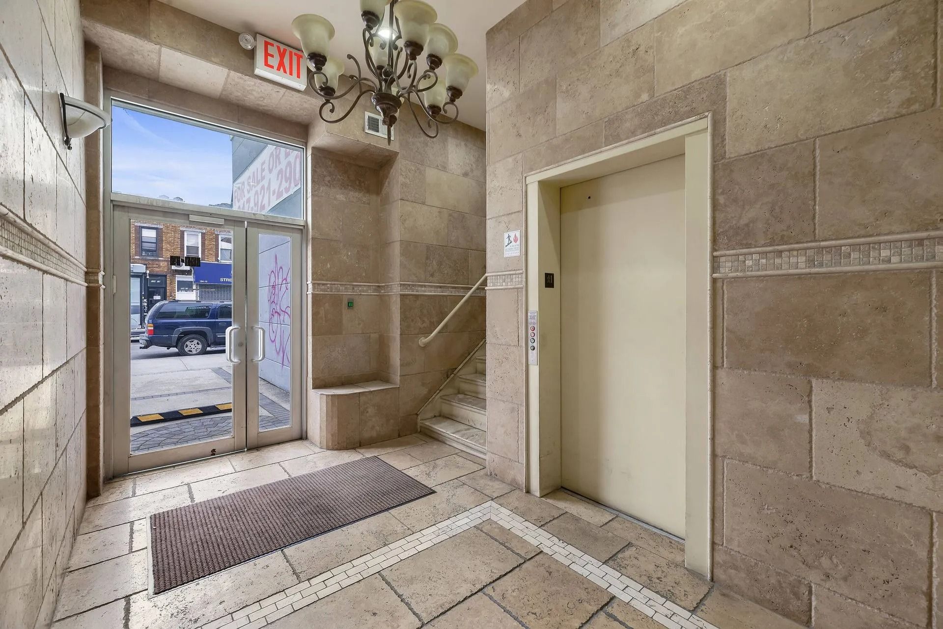 Lobby entrance with open door, elevator, and stone tile walls and floor.