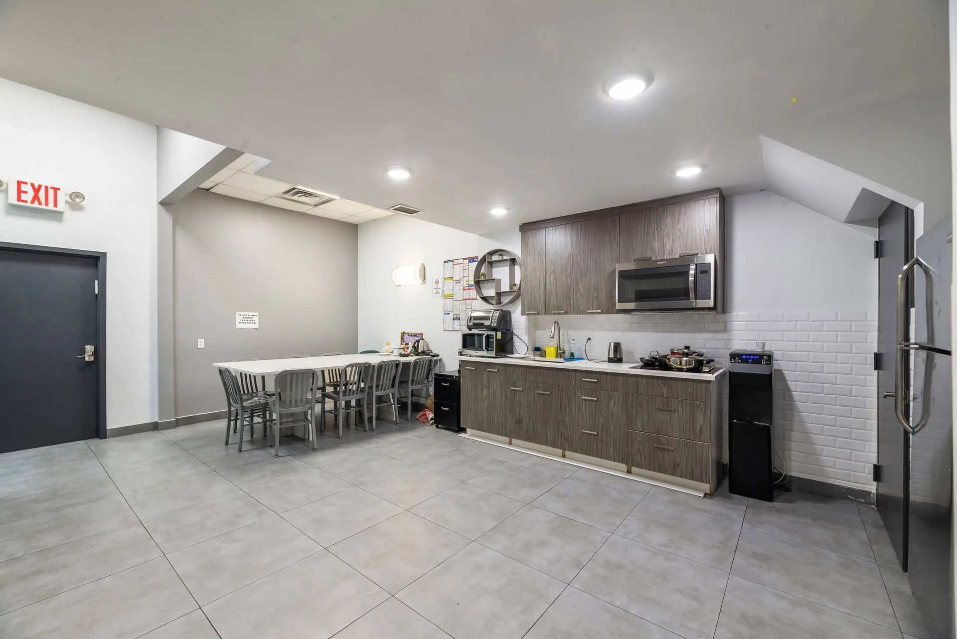 Modern kitchen and dining area with gray tile floor, island counter, table, and exit door