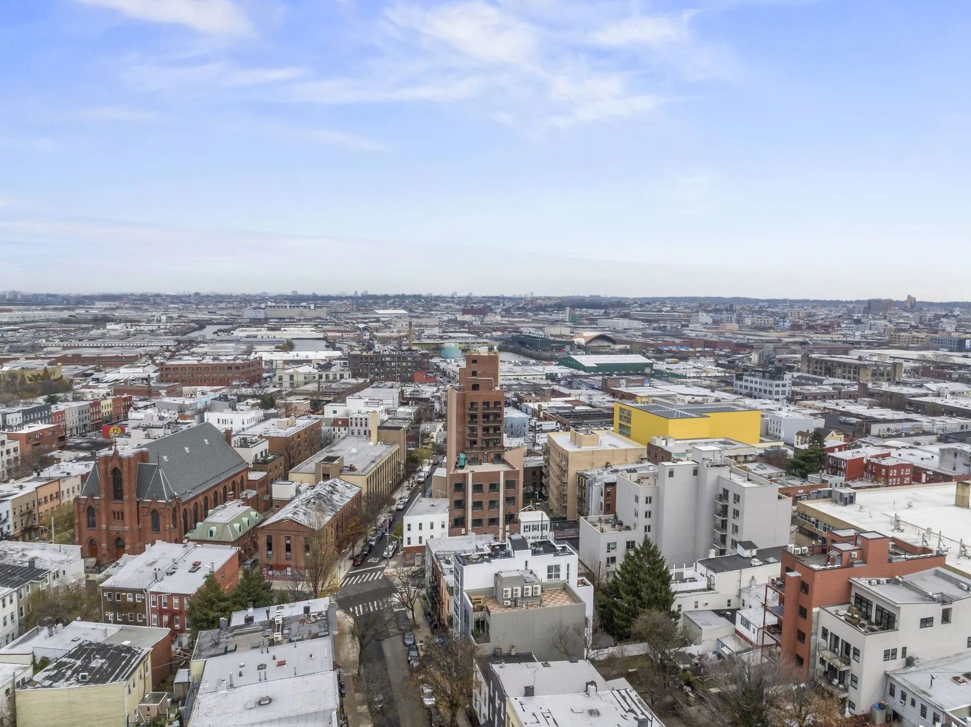 Snow-covered cityscape with brick buildings and a tall church tower under a cloudy sky