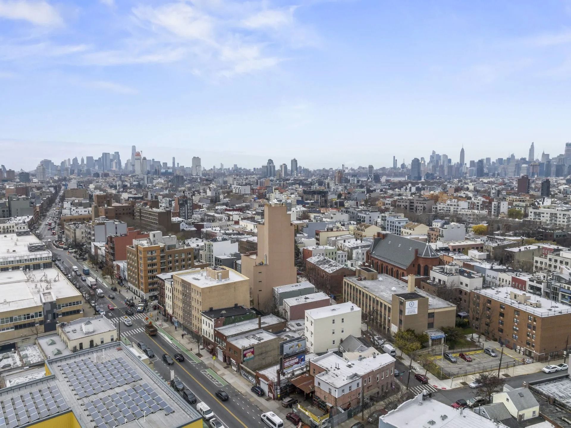 Aerial view of a snowy city neighborhood with skyline in the distance under a clear sky