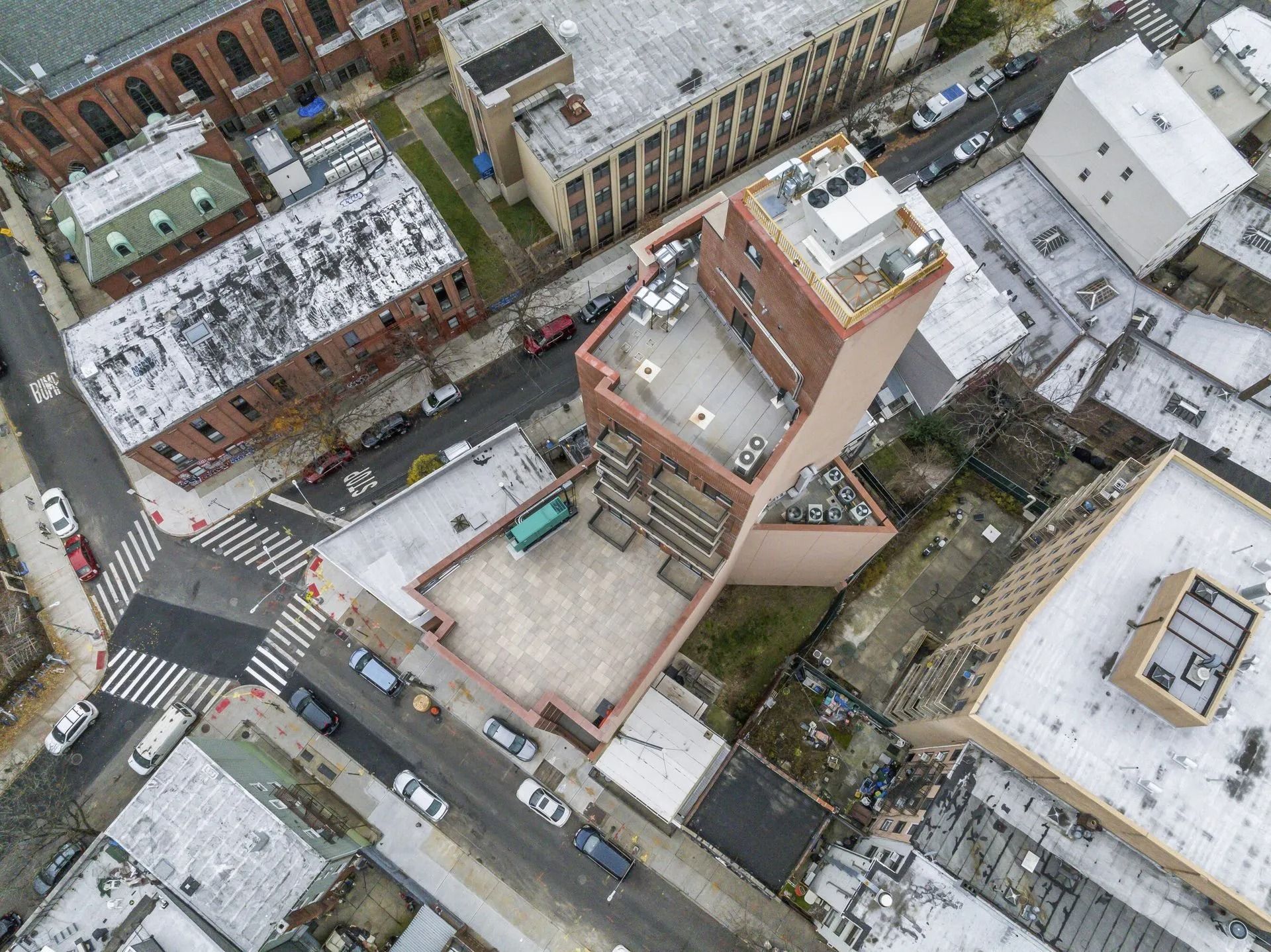 Aerial view of a snowy urban block with streets, buildings, and a central courtyard under construction.