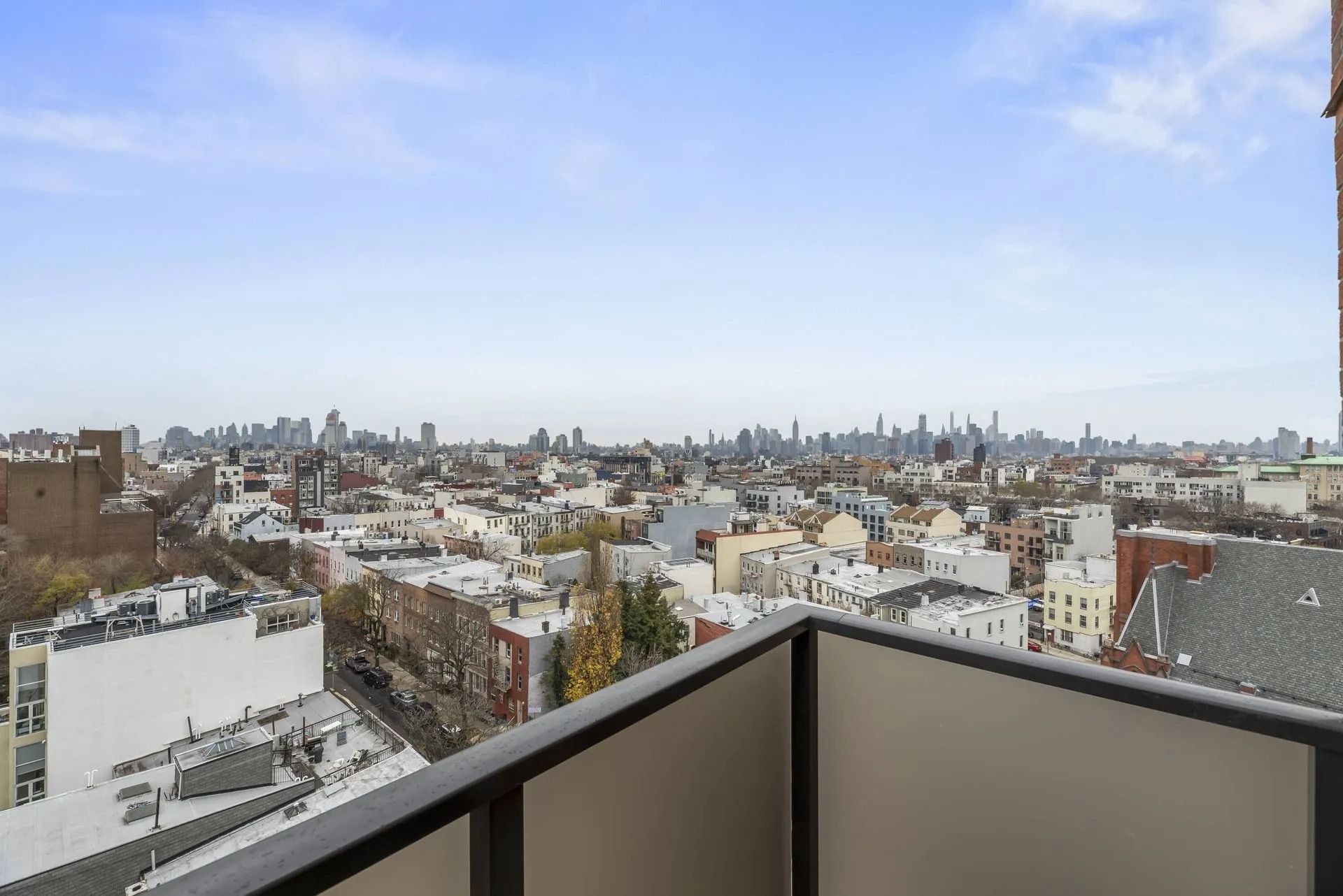 City skyline view from a balcony with rooftops and a bright blue sky