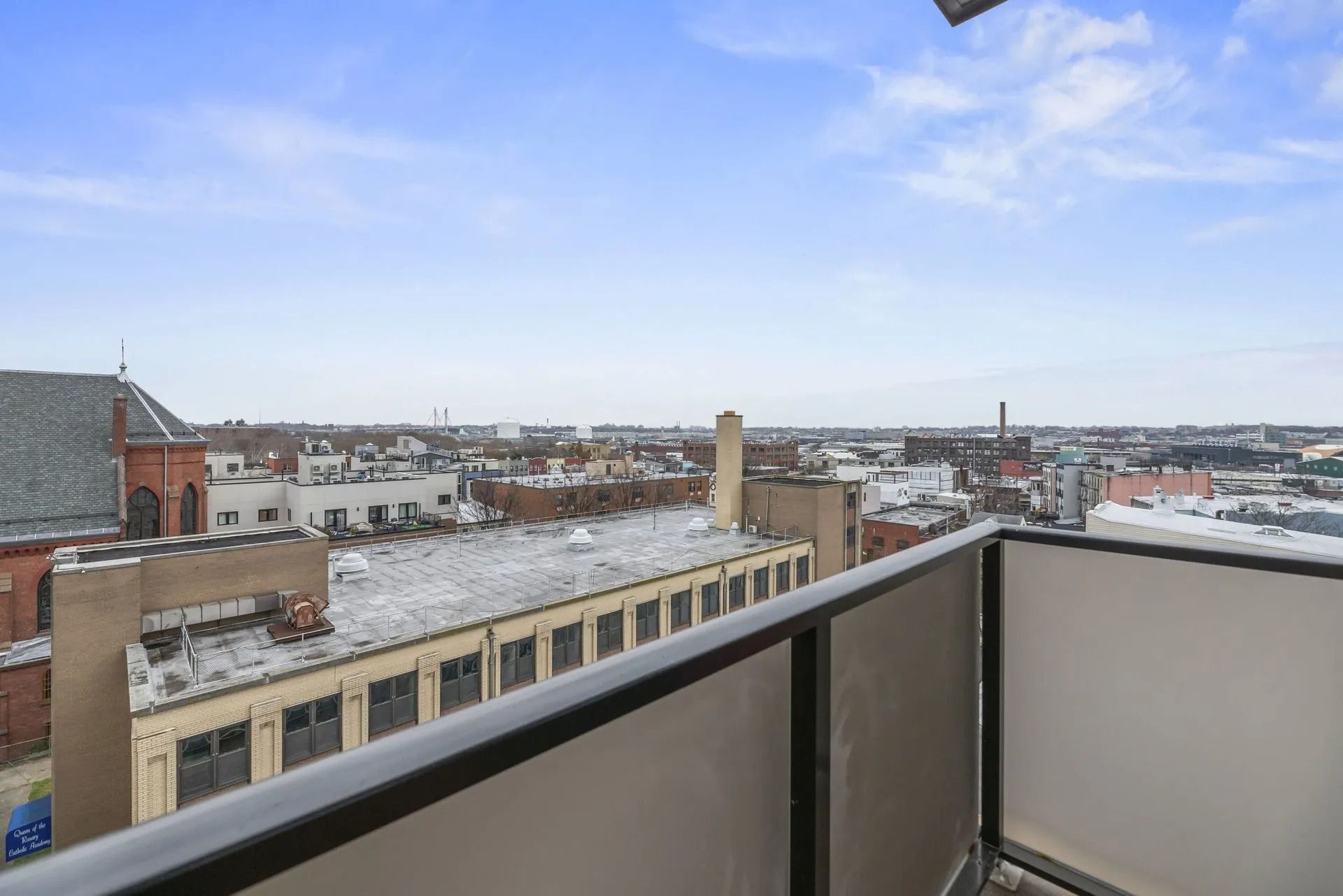 Rooftop balcony view over snowy city buildings under a blue sky