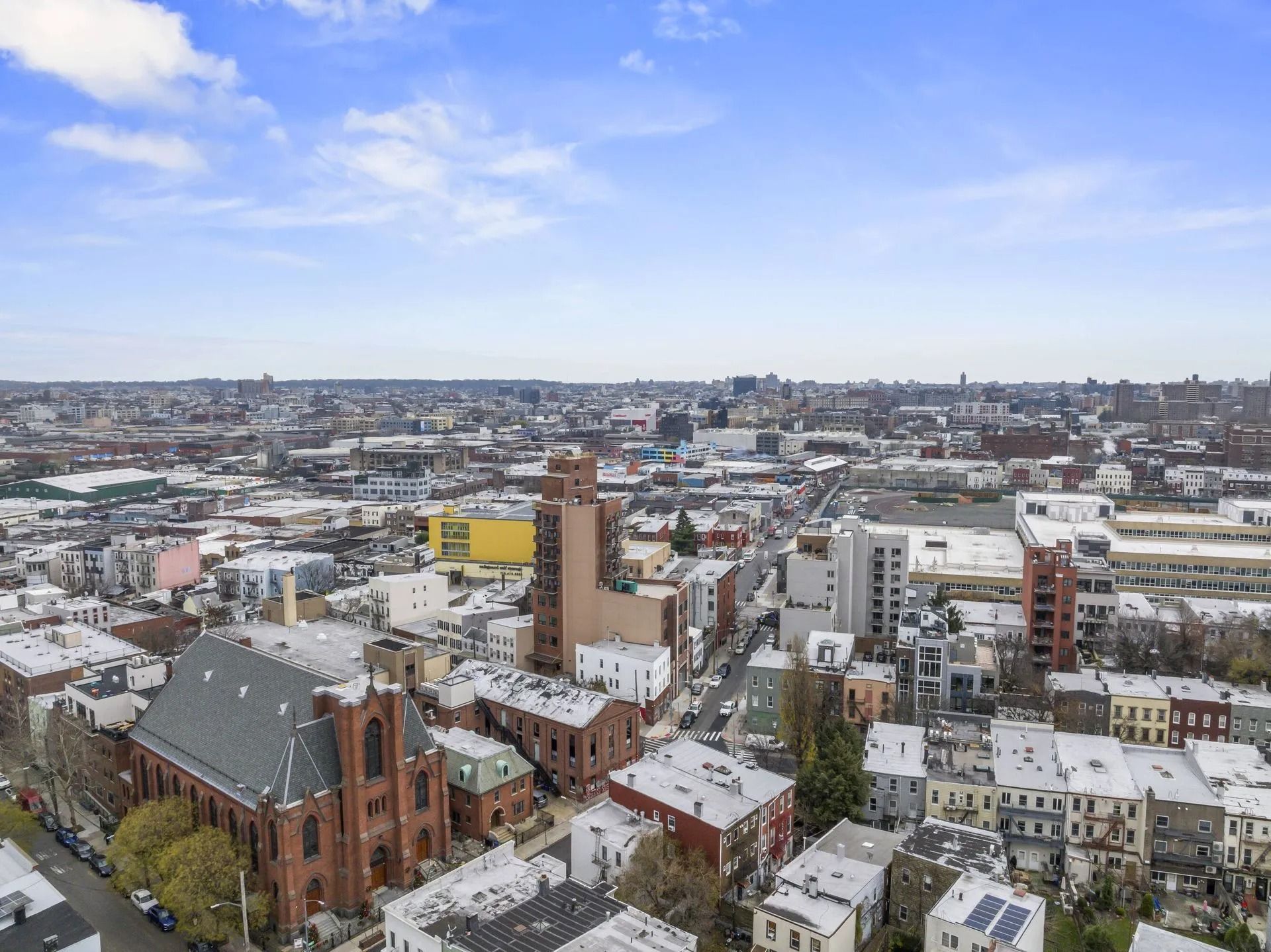 Snowy cityscape with red-brick church, tall tower, and dense buildings under a blue sky