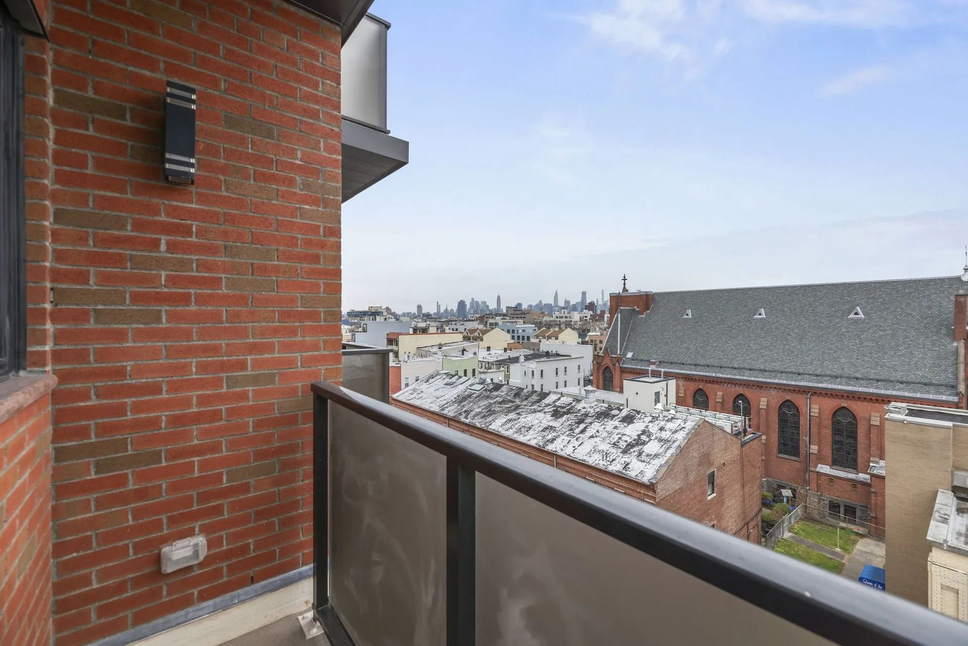 View from a balcony over brick buildings and a city skyline on a cloudy day
