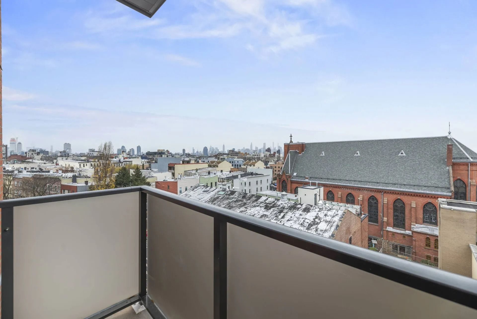 Balcony overlooking a snowy cityscape with rooftops and a cloudy sky