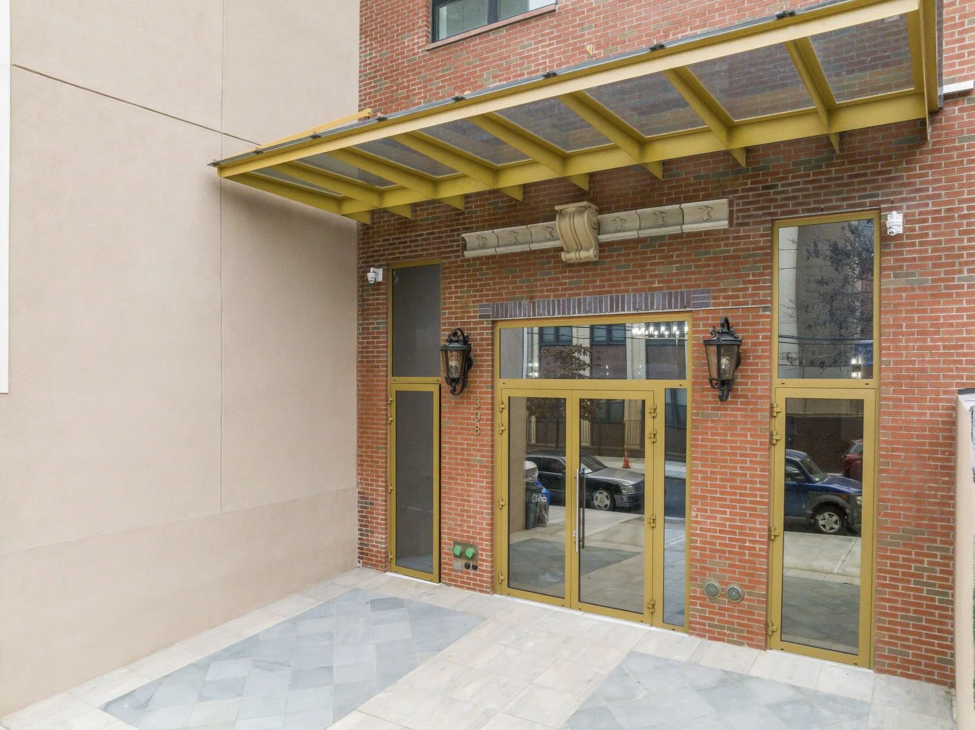 Brick storefront entrance with glass doors, yellow awning, and stone walkway