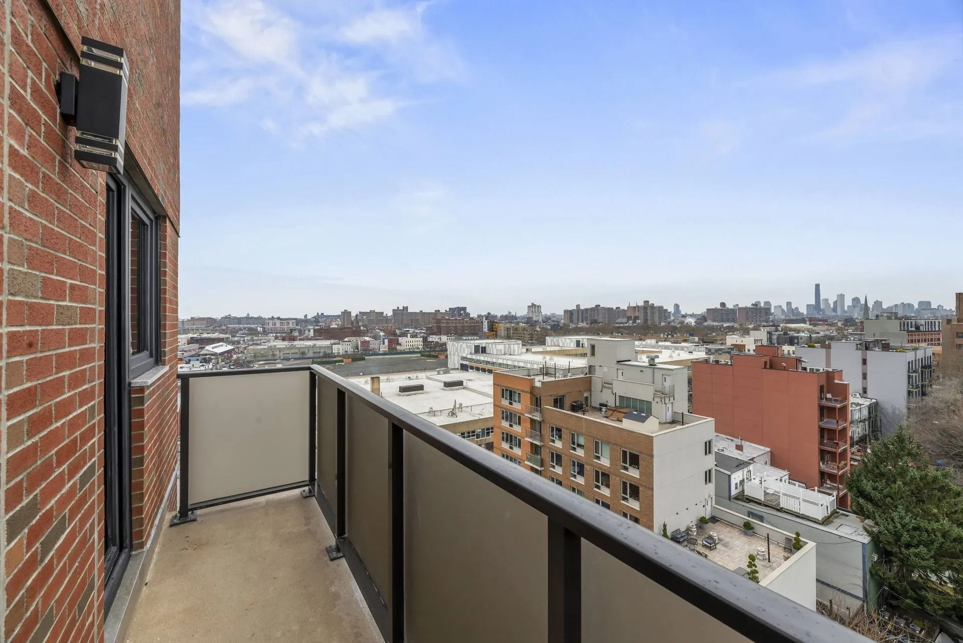Balcony view over city rooftops and skyline beside a brick building