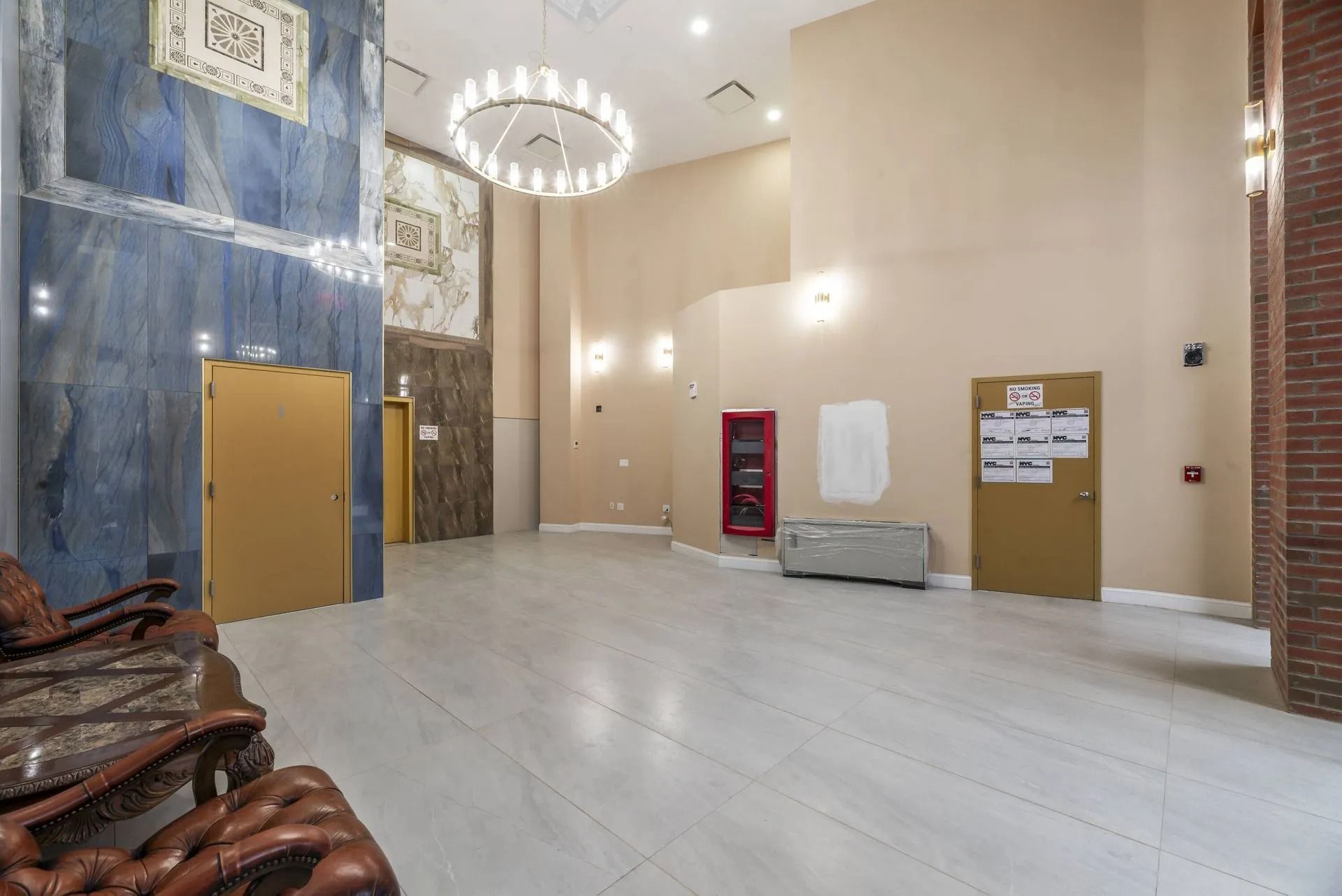 Spacious lobby with marble floors, chandelier, blue accent wall, tan doors, and a red vending machine.
