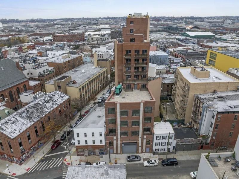 Aerial view of a snowy urban neighborhood with brick buildings and streets.