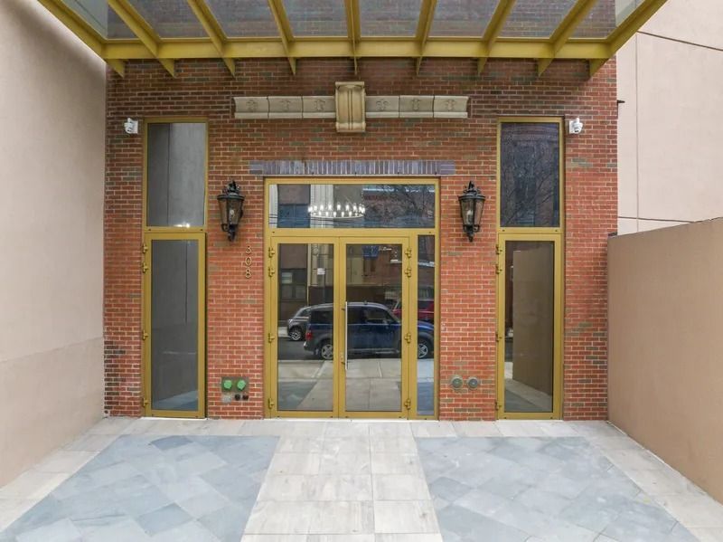 Brick building entrance with gold-framed double glass doors and side windows under a covered porch